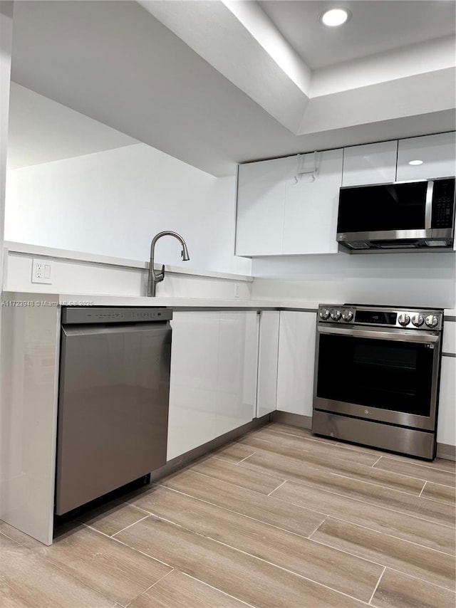 kitchen with stainless steel appliances, white cabinetry, and sink