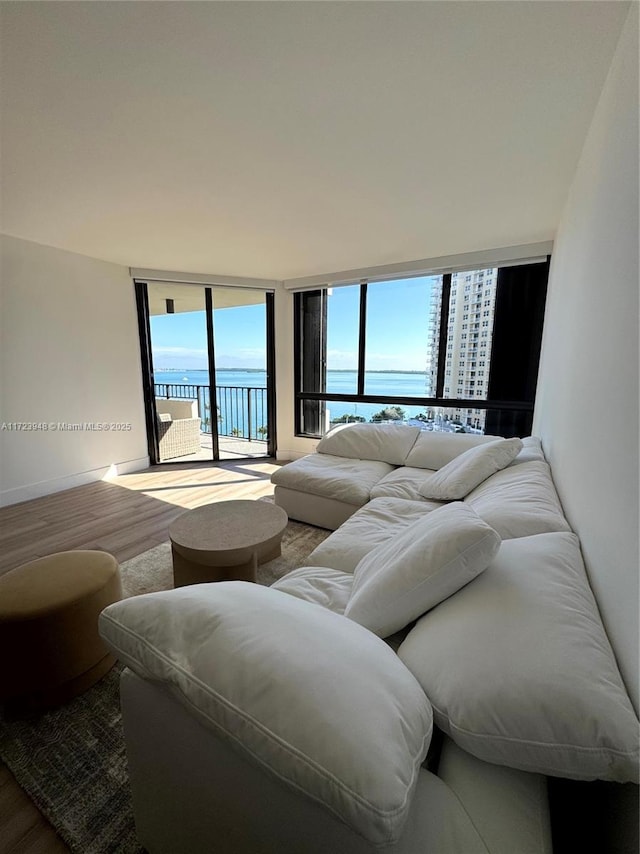 bedroom with hardwood / wood-style flooring, expansive windows, a water view, and access to exterior