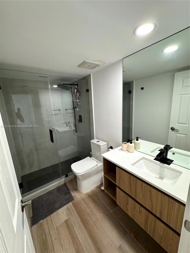 bathroom featuring vanity, toilet, and a shower with shower door