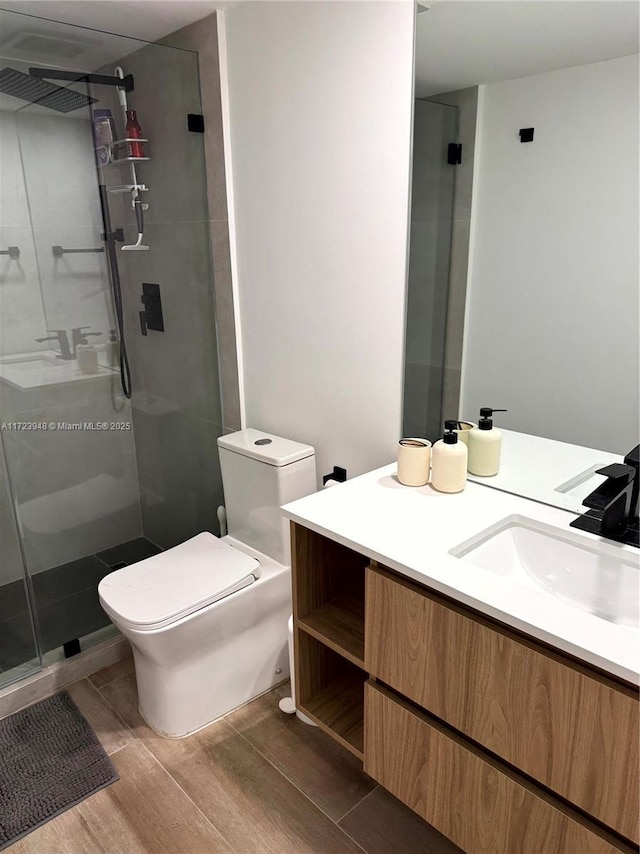 bathroom featuring vanity, toilet, and a shower with door