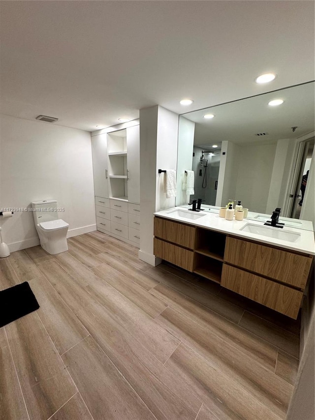 bathroom with hardwood / wood-style floors, vanity, and a shower with door