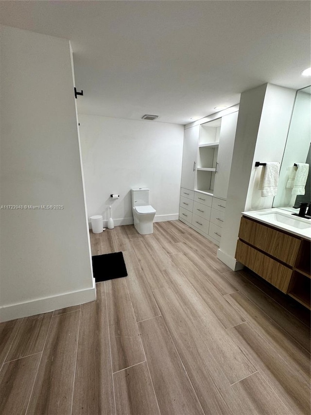 bathroom with wood-type flooring, vanity, and toilet