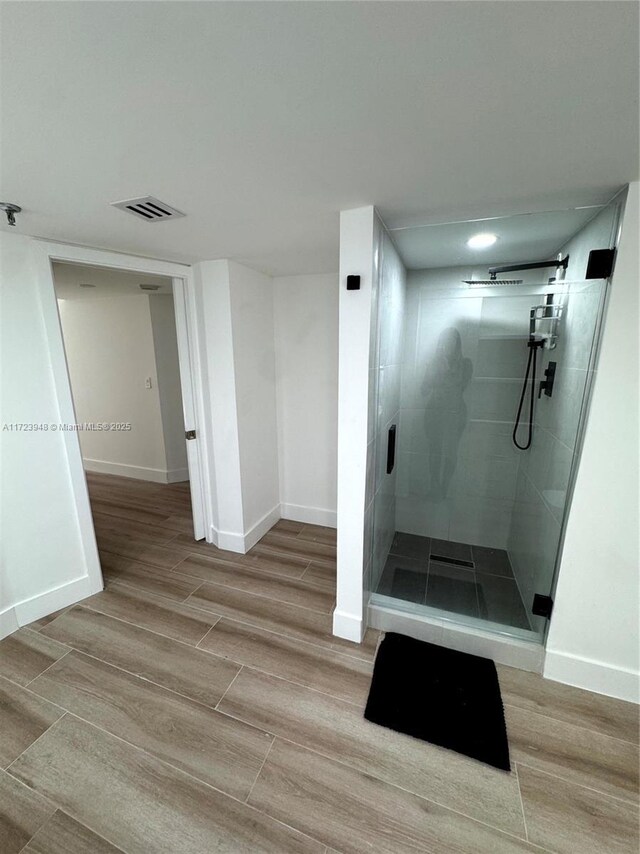 bathroom with a tile shower and wood-type flooring