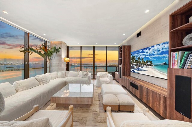 dining area with a water view, light hardwood / wood-style flooring, and a wall of windows