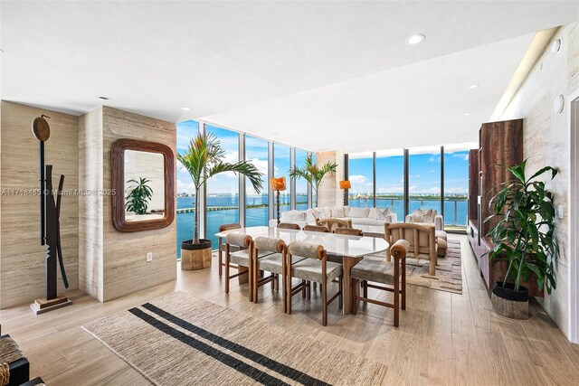 corridor featuring elevator, floor to ceiling windows, and light hardwood / wood-style floors