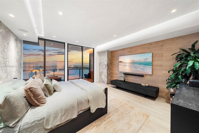 bedroom featuring access to exterior, light hardwood / wood-style floors, and floor to ceiling windows