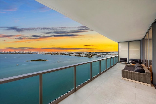 balcony at dusk featuring a water view