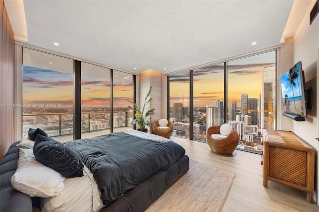 bedroom with access to outside, expansive windows, and light hardwood / wood-style floors