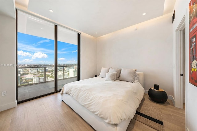 bedroom with access to exterior, light hardwood / wood-style floors, and floor to ceiling windows