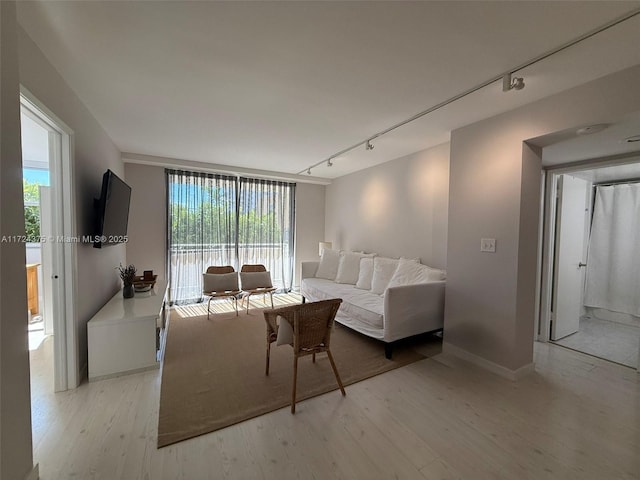 living room with light wood-type flooring, track lighting, and floor to ceiling windows