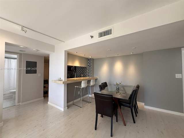 dining area with light wood-type flooring and rail lighting