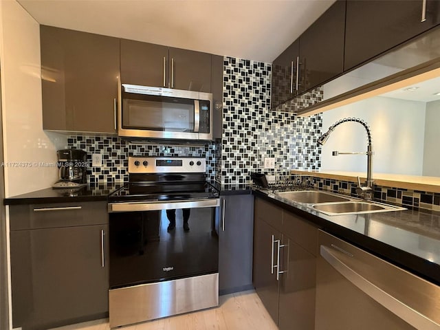 kitchen with decorative backsplash, appliances with stainless steel finishes, sink, and light hardwood / wood-style floors