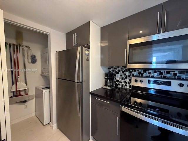 kitchen with tasteful backsplash, stacked washer and dryer, and stainless steel appliances