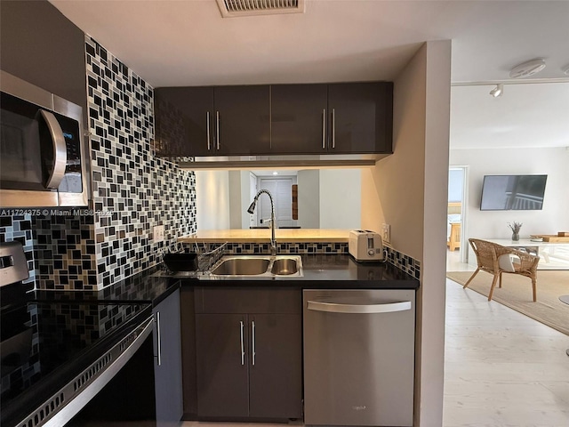 kitchen with light wood-type flooring, appliances with stainless steel finishes, dark brown cabinetry, and sink