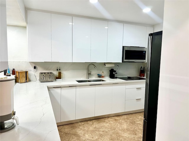 kitchen with sink, white cabinetry, decorative backsplash, light stone countertops, and appliances with stainless steel finishes