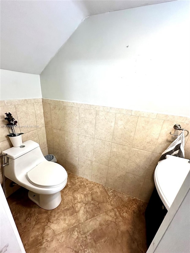 bathroom featuring tile walls, lofted ceiling, and toilet