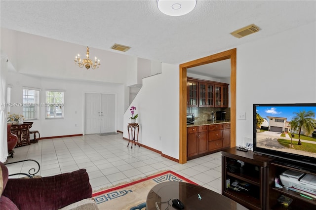 living room featuring light tile patterned floors, visible vents, and a textured ceiling