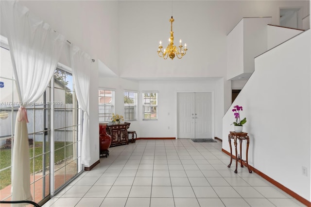 foyer entrance featuring baseboards, a high ceiling, light tile patterned flooring, and an inviting chandelier