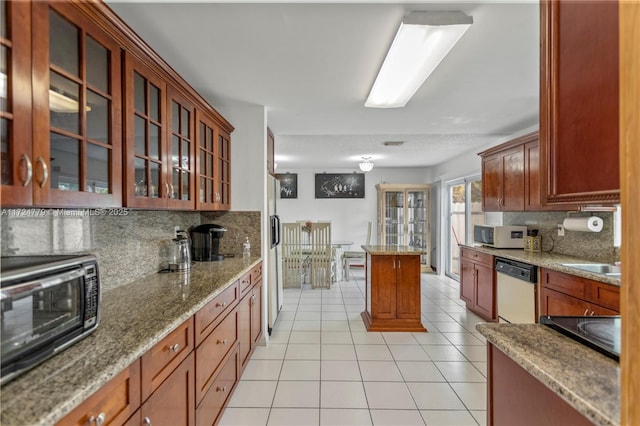 kitchen featuring light tile patterned floors, white appliances, decorative backsplash, light stone countertops, and glass insert cabinets