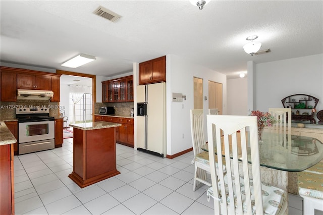 kitchen featuring a center island, white refrigerator with ice dispenser, range with electric stovetop, visible vents, and under cabinet range hood