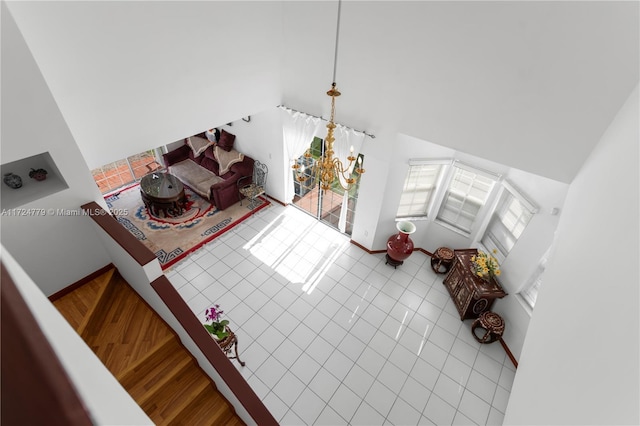 living room featuring high vaulted ceiling, an inviting chandelier, tile patterned flooring, and baseboards