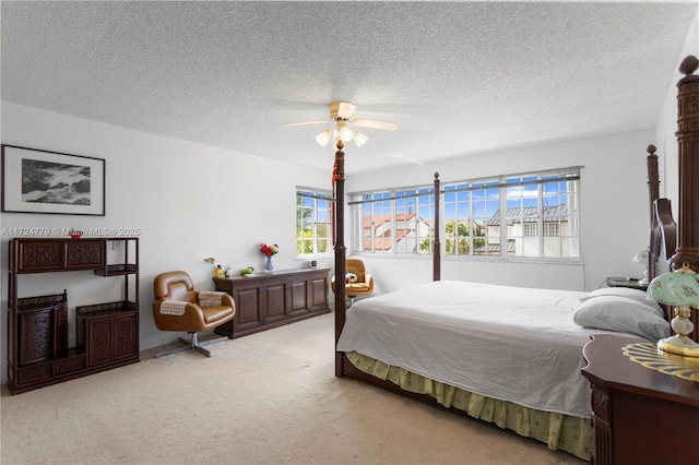 carpeted bedroom featuring ceiling fan and a textured ceiling