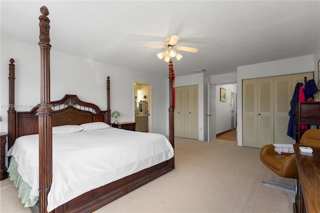 bedroom with light carpet, connected bathroom, a ceiling fan, a textured ceiling, and multiple closets