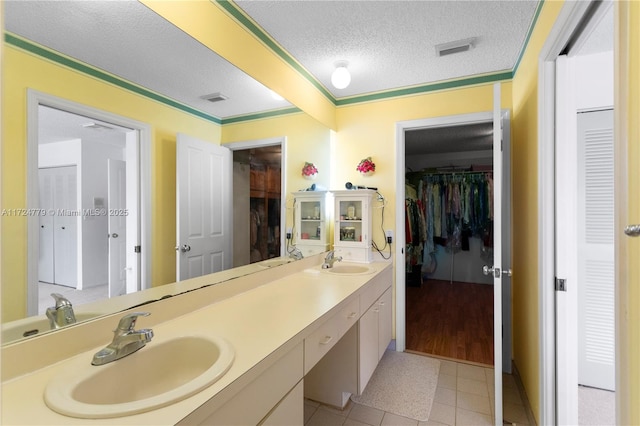 full bath featuring visible vents, a sink, a textured ceiling, and double vanity