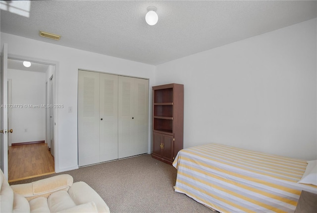 bedroom featuring a textured ceiling, carpet floors, a closet, and visible vents