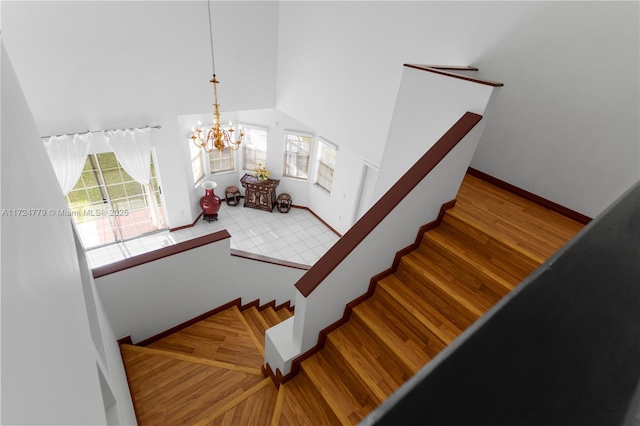 staircase featuring a high ceiling, plenty of natural light, wood finished floors, and baseboards