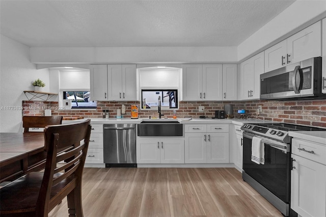 kitchen featuring white cabinetry, sink, light wood-type flooring, and appliances with stainless steel finishes