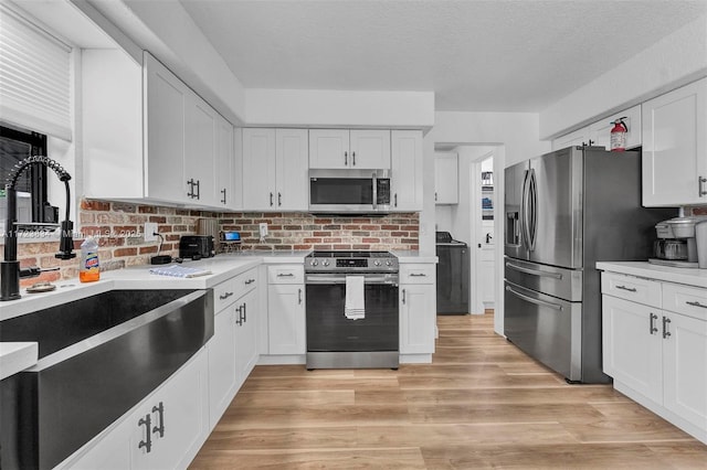 kitchen with white cabinets, appliances with stainless steel finishes, and light hardwood / wood-style flooring