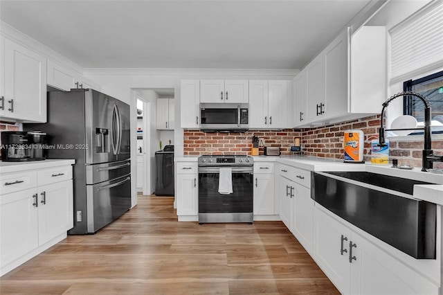 kitchen with white cabinetry, sink, stainless steel appliances, light hardwood / wood-style flooring, and backsplash