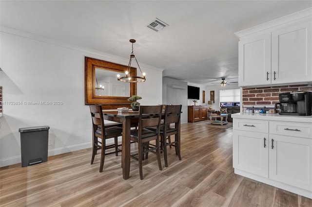 dining room with ceiling fan with notable chandelier, ornamental molding, and light hardwood / wood-style flooring