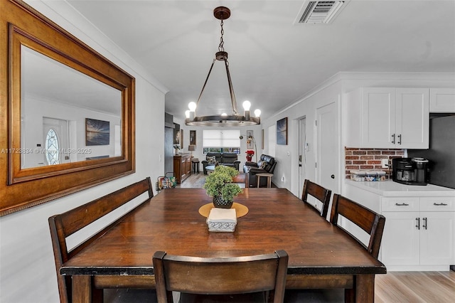 dining space featuring crown molding, light hardwood / wood-style flooring, and a chandelier