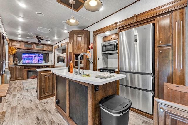 kitchen featuring sink, a center island, hanging light fixtures, light hardwood / wood-style floors, and appliances with stainless steel finishes