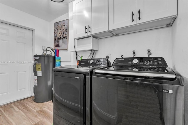 laundry room with cabinets, electric water heater, light hardwood / wood-style flooring, and washing machine and clothes dryer