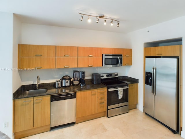 kitchen featuring sink, light tile patterned floors, stainless steel appliances, and dark stone counters