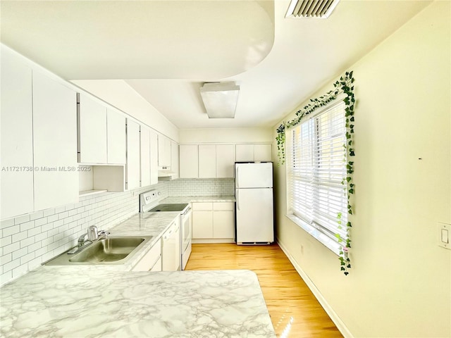 kitchen featuring white appliances, visible vents, a sink, light countertops, and backsplash