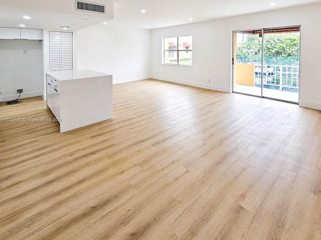 unfurnished living room featuring a healthy amount of sunlight and light hardwood / wood-style floors