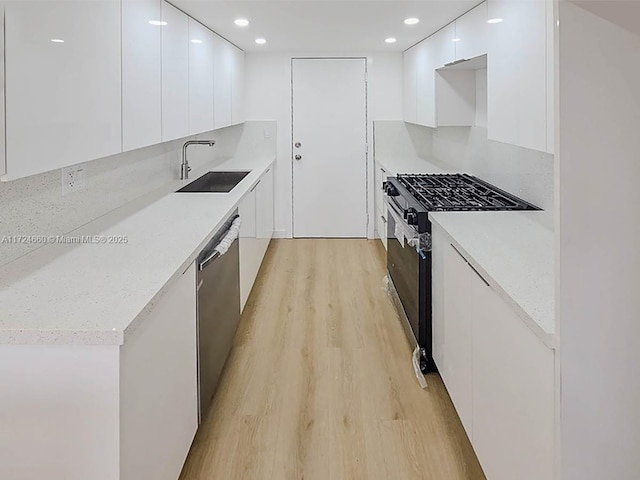 kitchen with white cabinets, sink, light hardwood / wood-style flooring, stainless steel dishwasher, and black range with gas cooktop