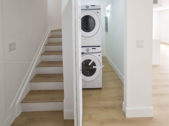 washroom with stacked washer and dryer and wood-type flooring