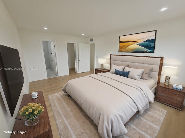 bedroom featuring ensuite bathroom and light hardwood / wood-style flooring