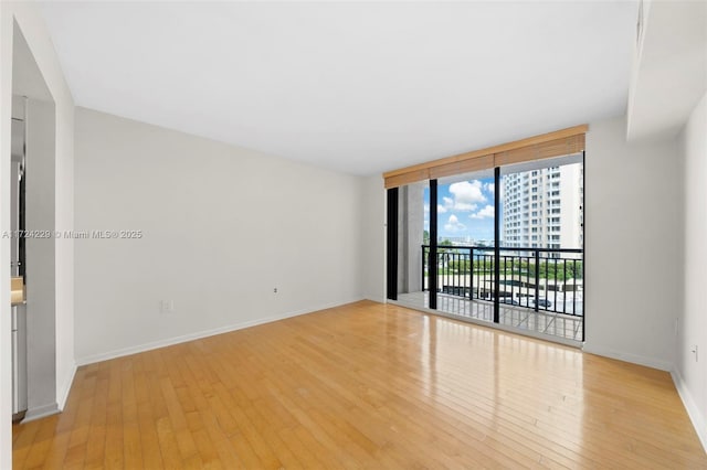 empty room with floor to ceiling windows and light wood-type flooring