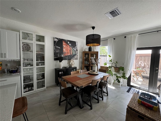 dining space with a textured ceiling and light tile patterned floors