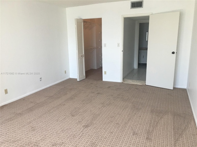 unfurnished bedroom featuring a spacious closet, carpet floors, and a closet