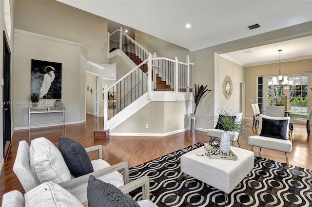 living room featuring wood-type flooring, a notable chandelier, and crown molding