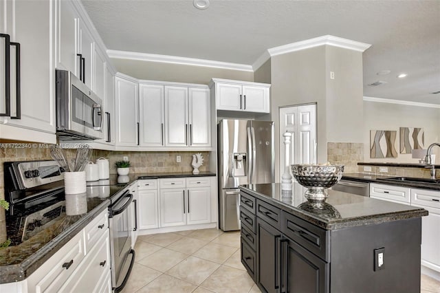 kitchen featuring sink, appliances with stainless steel finishes, dark stone countertops, white cabinets, and a kitchen island