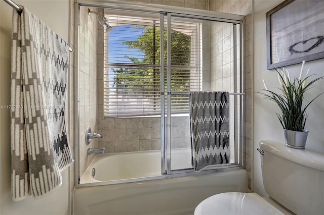 bathroom with toilet and combined bath / shower with glass door