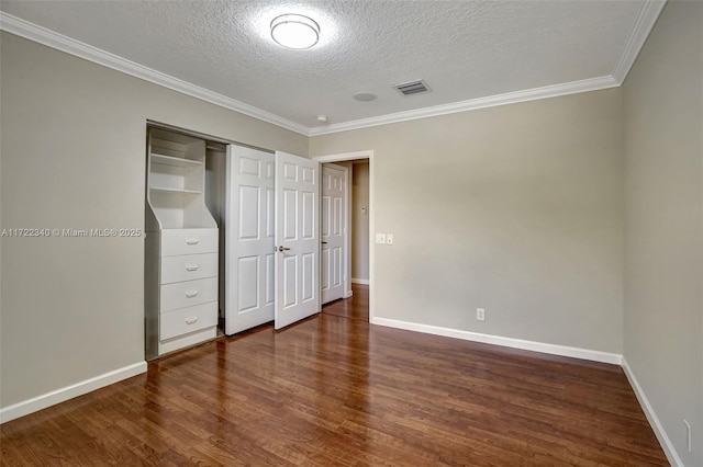 unfurnished bedroom featuring dark wood-type flooring, ornamental molding, a closet, and a textured ceiling